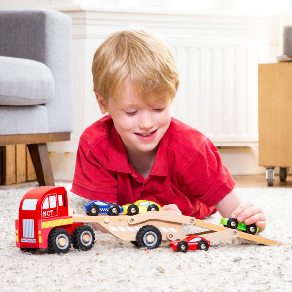 educatief-rollenspel-houten-voertuig Kind speelt met houten autotransporter op vloer