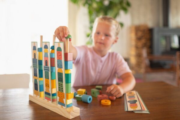 Jongen speelt het spel stapeltorens met alle houten blokken.