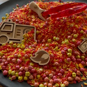 De inhoud van de pot sensorische materialen pourandplay Fire op een houten ondergrond
