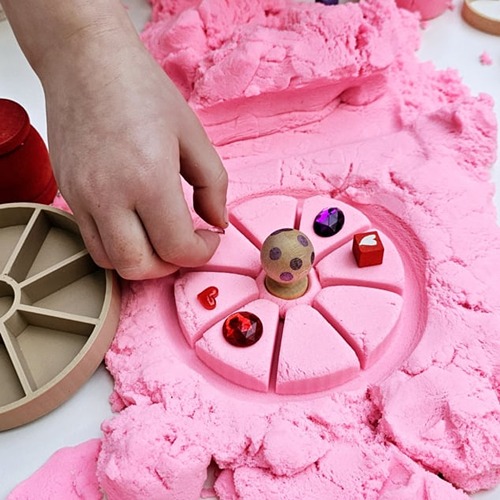Plat stuk magic sand Sensoryfun met bloem afdruk en versierd met loose parts