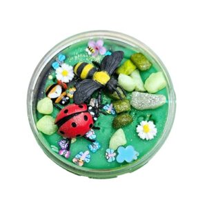 Groene sensorische klei, versierd met een plastic lieveheersbeestje, bij, kleurrijke steentjes, bloemetjes en kleine vlinders – vrolijke lentetuin in miniatuurformaat.